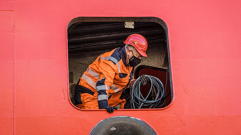 Arbeiter in Warnkleidung im inneren eines Schiffes.