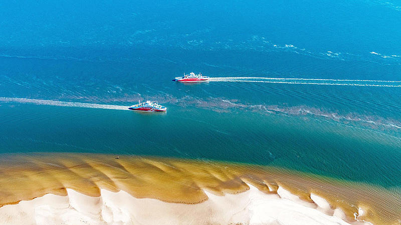 Die beiden Syltfähren fahren aneinander vorbei vorm Sandstrand.