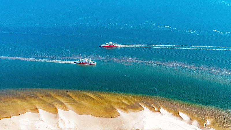 Both Syltferries passing each other next to the sand beach.