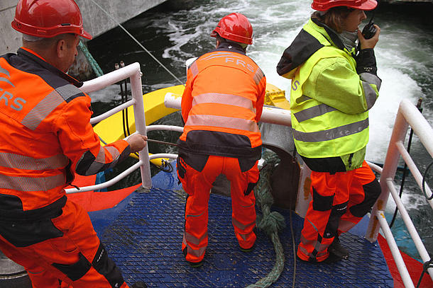 Crewmembers in orange safety vests. 