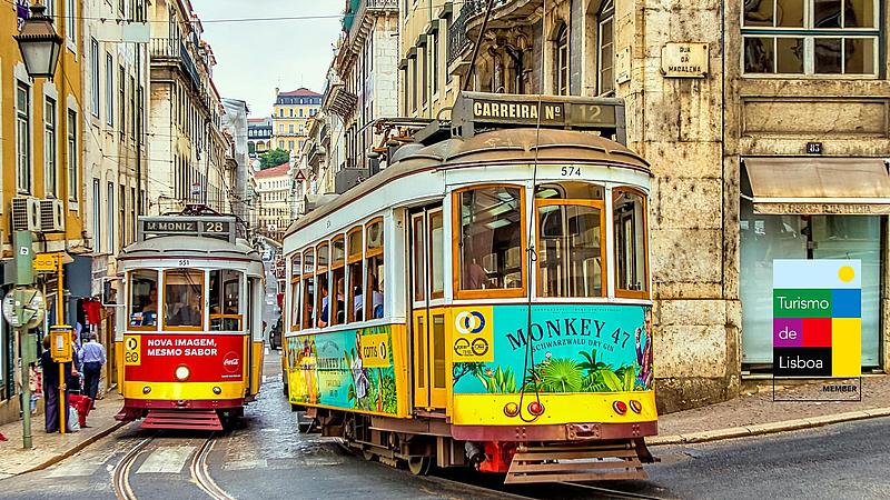 Zwei Straßenbahnen fahren durch ein Gasse in Lissabon.