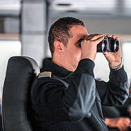 Captain with a pair of binoculars on the bridge.