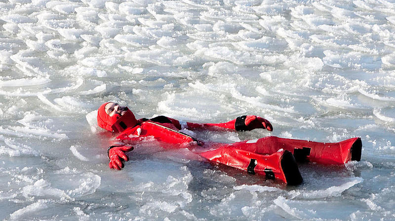 Eine Person im roten Anzug treibt im Eiswasser.