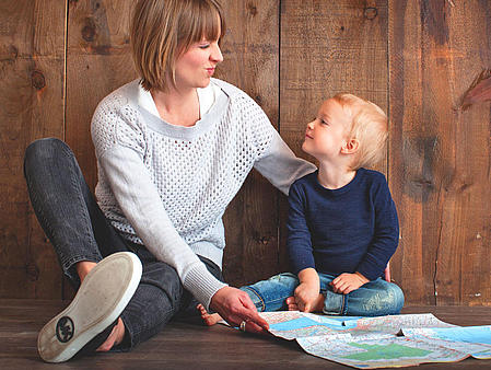 An adult and a baby, who are looking at a map.